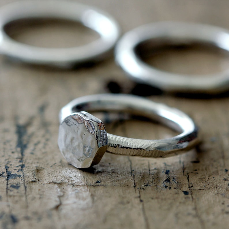 May include: A silver ring with a hammered, octagonal band and a textured, hexagonal top.