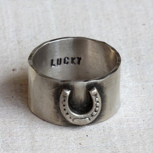 Lucky horseshoe ring. Sterling silver wide band ring with a horseshoe on the front and the word lucky engraved on the inside of the hammered band.