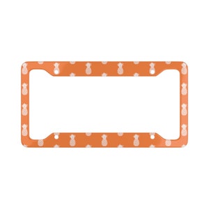 May include: Orange license plate frame with a white pineapple pattern.