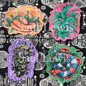 May include: Four colourful stickers featuring different snake designs. Each sticker has a different background colour and features a snake with floral elements. The stickers are perfect for adding a touch of whimsy to any surface.