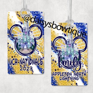 Könnte beinhalten: Zwei Gepäckanhänger mit einem blauen und goldenen Glitzerhintergrund. Die Anhänger zeigen eine Mickey-Maus-Silhouette mit dem Schloss von Aschenputtel im Inneren. Ein Anhänger sagt "UCA Nationals 2023" und der andere sagt "Emily Appleton North Lightning".