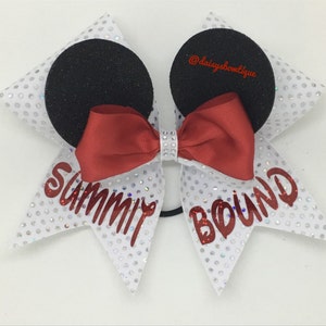 May include: White cheer bow with red and black accents. The bow has the words "Summit Bound" in red glitter lettering. The bow is decorated with silver glitter and rhinestones.