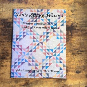 May include: A book titled "Let's Make Waves!" with complete instructions for making ocean waves quilts. The cover features a colorful geometric pattern in shades of blue, pink, and yellow. The authors' names, Marianne Fons and Liz Porter, are also visible.