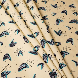 May include: Beige fabric with a repeating pattern of black and teal blue abstract shapes. The shapes resemble boomerangs with a small black line extending from the top.