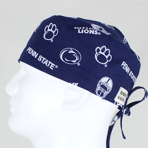Peut inclure: Un bonnet de chirurgien bleu marine avec un imprimé blanc du logo des Nittany Lions de Penn State, des empreintes de pattes et des casques de football. Le bonnet a une cravate à l'arrière.