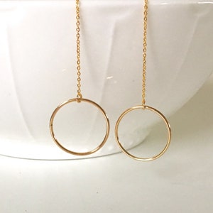 May include: A pair of gold dangle earrings with a circle pendant on each earring.