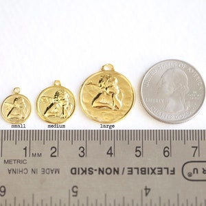 Puede incluir: Tres abalorios de &aacute;ngel dorados en diferentes tama&ntilde;os, siendo el m&aacute;s grande de aproximadamente 3,8 cm de di&aacute;metro. Los abalorios se muestran junto a una moneda de 25 centavos de d&oacute;lar estadounidense para comparar el tama&ntilde;o.