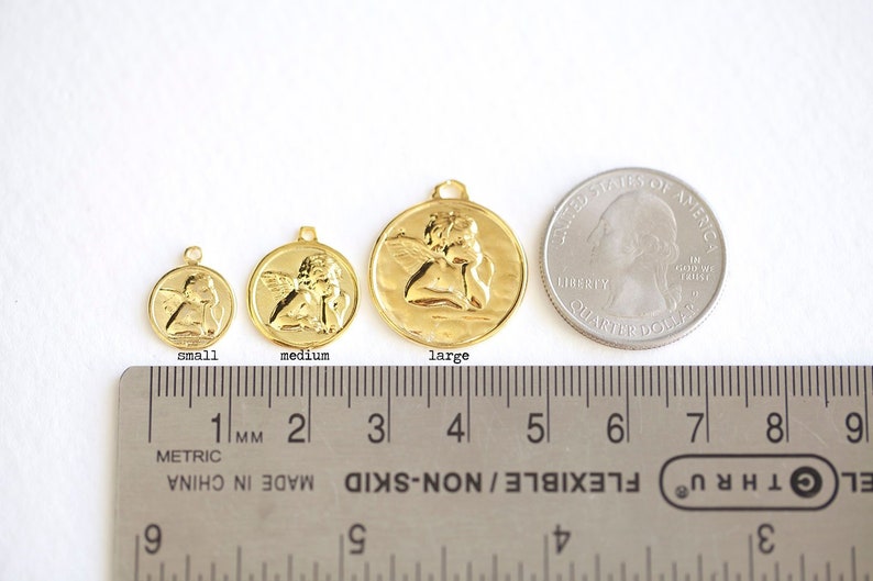 Puede incluir: Tres abalorios de &aacute;ngel dorados en diferentes tama&ntilde;os, siendo el m&aacute;s grande de aproximadamente 3,8 cm de di&aacute;metro. Los abalorios se muestran junto a una moneda de 25 centavos de d&oacute;lar estadounidense para comparar el tama&ntilde;o.