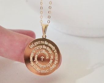 May include: Gold necklace with a round pendant featuring the Serenity Prayer engraved in a circle. The prayer reads: "God grant me the serenity to accept the things I cannot change, courage to change the things I can, and the wisdom to know the difference."