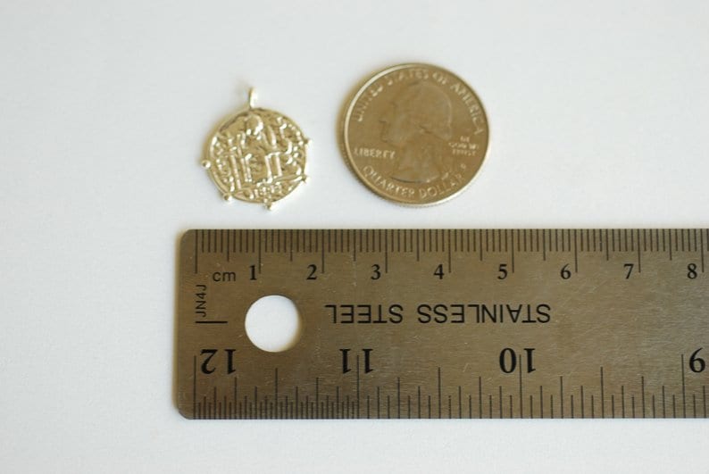 May include: Silver pendant charm with a detailed design of three figures, measuring approximately 1 inch in diameter. The pendant is shown next to a US quarter for size comparison.