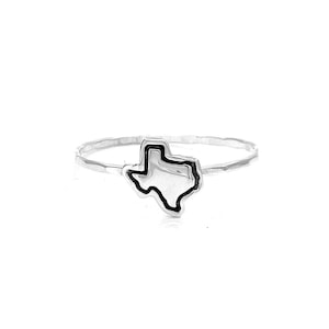 Sterling silver stacking ring featuring a detailed Texas charm. The ring has a thin, hammered band with the Texas state outline prominently displayed in the center. Ideal for Texans and those who love the Lone Star State