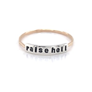 May include: A gold and silver ring with the words "raise hell" engraved on it.