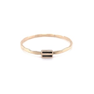 May include: A gold-colored ring with a hammered texture and a rectangular black inlay. The ring is a simple band design, suitable for everyday wear. The ring is shown on a white background.