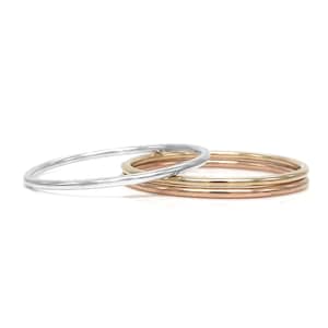 May include: Three thin stacking rings, one silver and two gold.