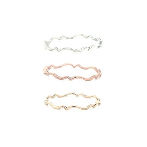 May include: Three wavy rings in different metal finishes: silver, rose gold, and gold.