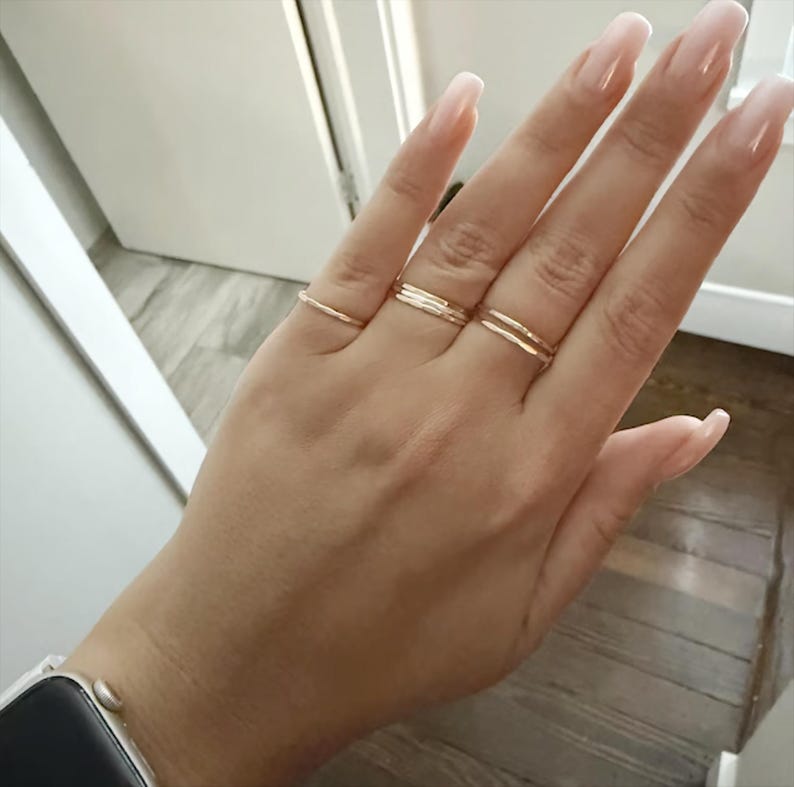 A customer showcasing our hammered stacking rings worn across multiple fingers, creating a bold and stylish statement that highlights the versatility of these handmade pieces.