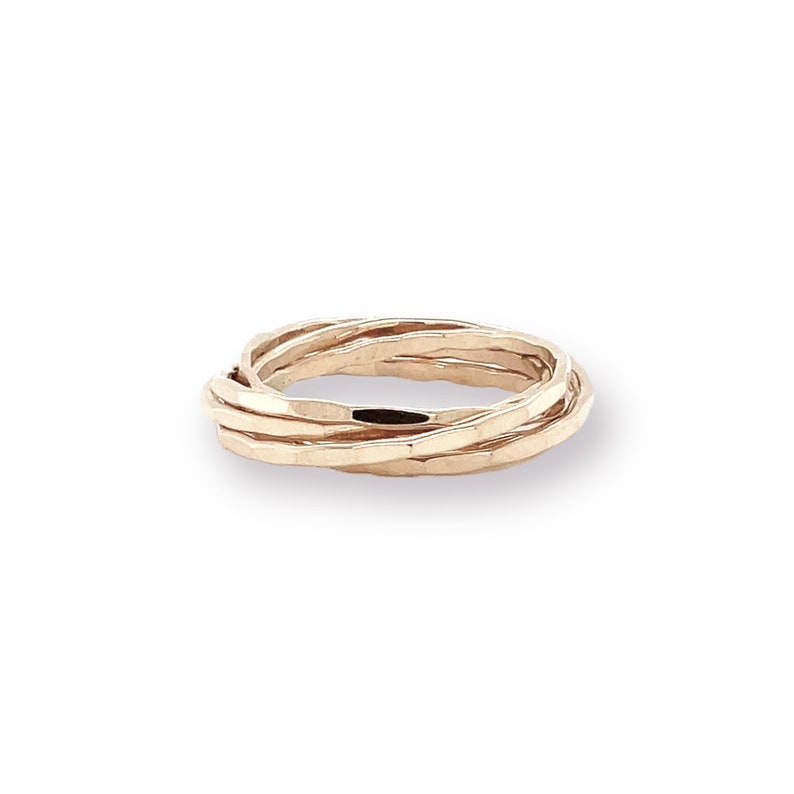 K&ouml;nnte beinhalten: Ein goldfarbener Ring mit geh&auml;mmertem Muster. Der Ring besteht aus f&uuml;nf ineinander verschlungenen B&auml;ndern, die ein gewebtes Aussehen erzeugen. Die B&auml;nder sind etwa 0,6 cm breit, das Design ist schlicht und elegant.