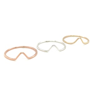 May include: Three simple minimalist rings with a V-shaped design. The rings are made of silver, gold, and rose gold.