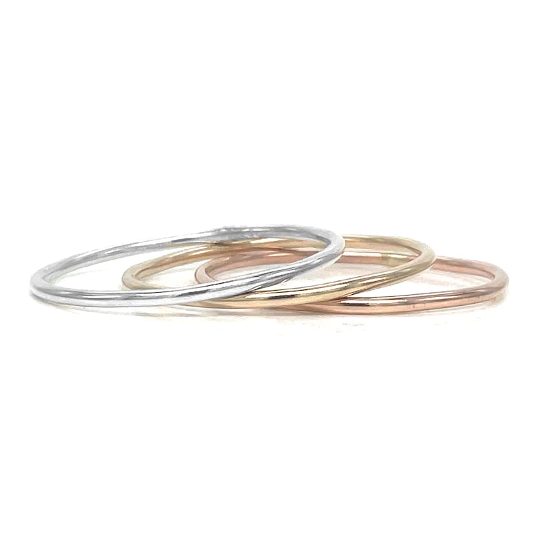 May include: Three thin stacking rings in silver, gold, and rose gold.