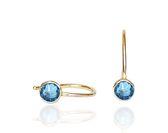 May include: A pair of gold hoop earrings with a blue gemstone in each earring.
