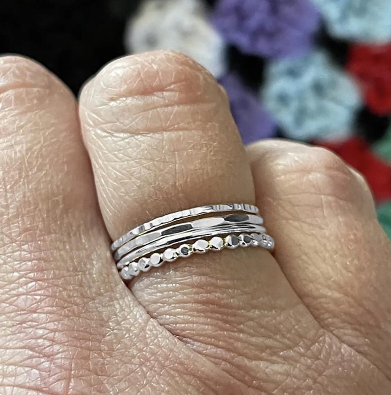 Layered on one finger, a customer wears multiple hammered rings to create a personalized look that reflects individual style and creativity.