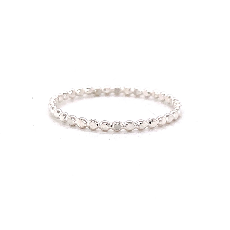 May include: A delicate silver ring with a beaded design. The ring is made of small, round beads that are evenly spaced along the band.
