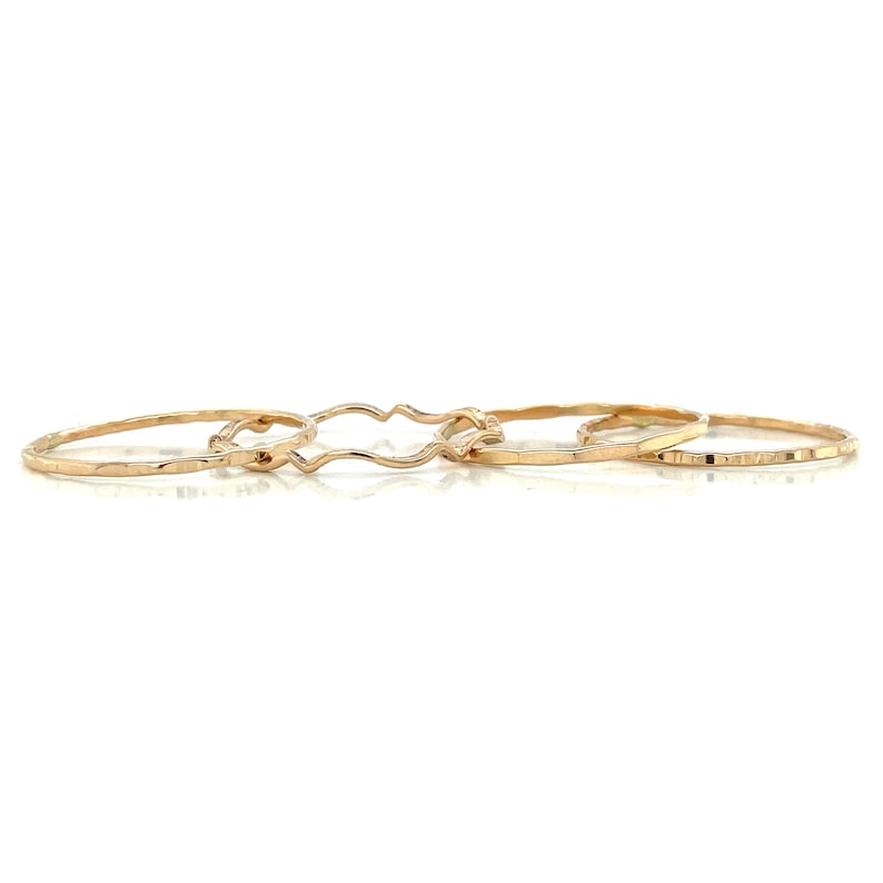 May include: Three gold rings, one with a wavy design, one with a hammered texture, and one with a textured edge.