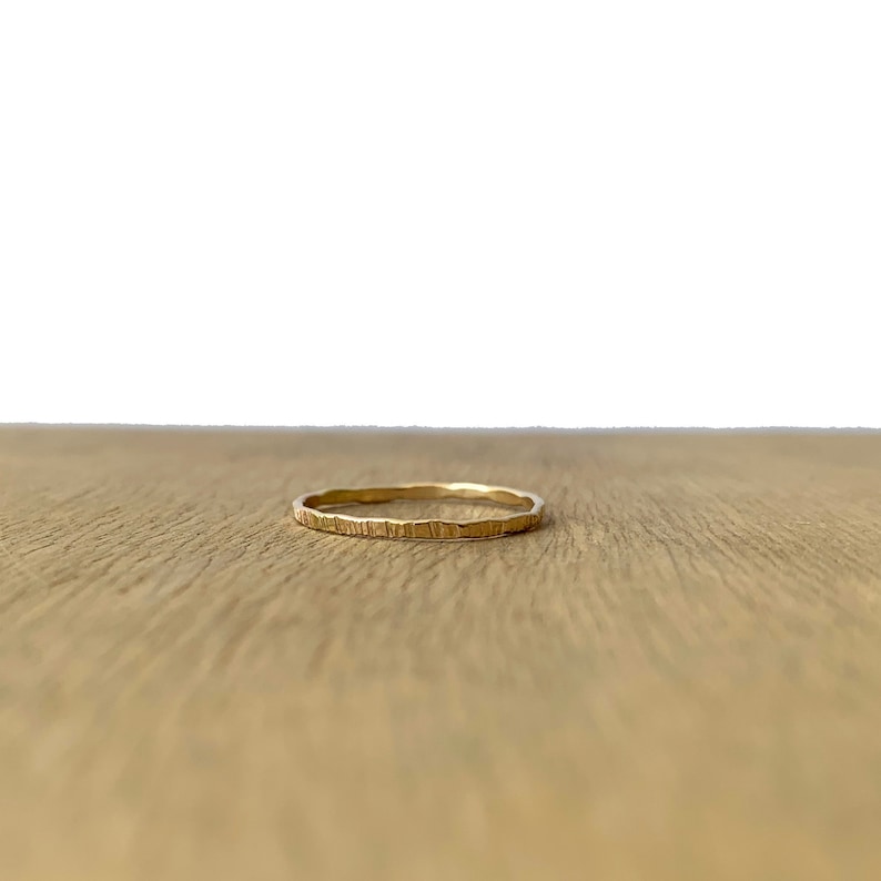 May include: A thin gold band ring with a hammered texture.