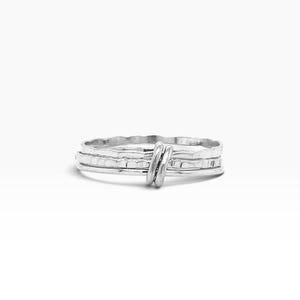 May include: A silver ring featuring a multi-band design with a textured, hammered finish. The bands are held together by a small, smooth silver wire wrap detail that secures the individual components into a single cohesive piece of jewelry.