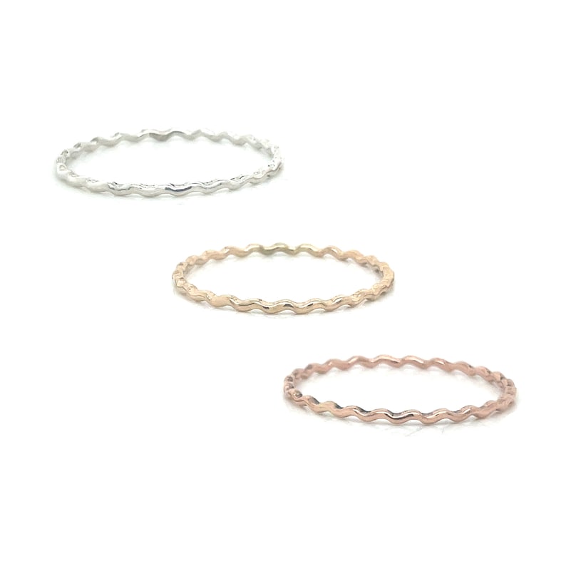 May include: Three thin wavy rings in silver, gold, and rose gold.