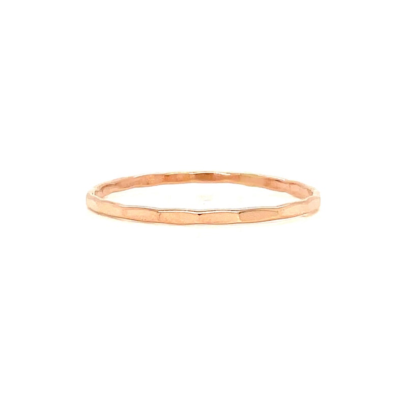 May include: A delicate, hammered-style ring in a warm rose gold hue. The ring features a thin band with a textured surface, creating a subtle, yet eye-catching design. This piece of jewelry is perfect for everyday wear or as a minimalist statement.