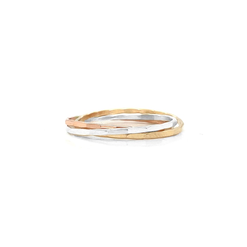 K&ouml;nnte beinhalten: Ein Satz von drei geh&auml;mmerten Metallringen in Gold, Silber und Ros&eacute;gold. Die Ringe sind &uuml;bereinander gestapelt und zeigen ihre unterschiedlichen Farben und Texturen. Es handelt sich wahrscheinlich um Schmuck.