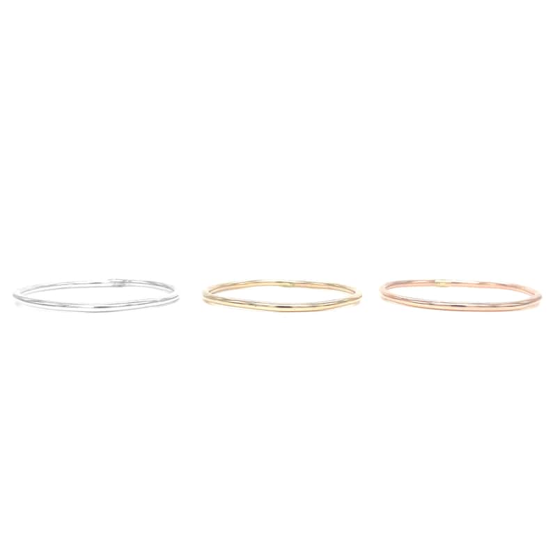 May include: Three simple, thin, minimalist rings in silver, gold, and rose gold.
