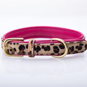 Op de afbeelding: Een hondenriem met een felroze leren binnenkant en een luipaardprint aan de buitenkant. De halsband heeft een goudkleurige metalen gesp en een bijpassende lus. Ontworpen voor een middelgrote hond.