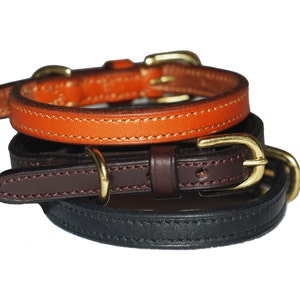 May include: Three leather dog collars stacked on top of each other. The top collar is orange, the middle collar is brown, and the bottom collar is black.