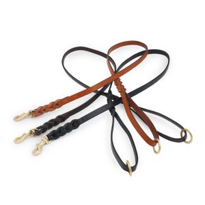 May include: Three leather dog leads, one black and two brown, with braided designs and brass clasps.