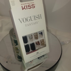 K&ouml;nnte beinhalten: Eine wei&szlig;e Schachtel mit KISS Voguish Fantasy Kunstn&auml;geln. Die Schachtel tr&auml;gt den Text "Bring the Salon Home" und "KISS". Die N&auml;gel sind schwarz, goldglitzernd und im Leopardenmuster. Die Schachtel enth&auml;lt auch den Text "28 NAILS/ONGLES/NAGELS/UNGHE/NAGELS GLUE INCLUDED".