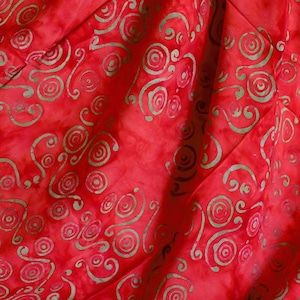 May include: Close-up of red fabric with a swirling, spiral pattern in a lighter, muted green. The fabric has a textured appearance, with visible folds and creases. The design is evenly distributed across the material, creating a visually dynamic textile.