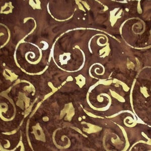 Könnte beinhalten: Nahaufnahme eines braunen Stoffes mit einem goldfarbenen, wirbelnden Blumenmuster. Das Design zeigt stilisierte Blätter und Spiralformen, die eine strukturierte, dekorative Oberfläche schaffen. Der Stoff hat ein gesprenkeltes Aussehen.