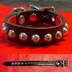 May include: Black leather dog collar with silver metal studs. The collar has a silver buckle and is adjustable.
