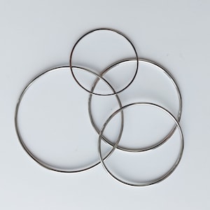 May include: Four silver metal hoops of different sizes, interlocked together.