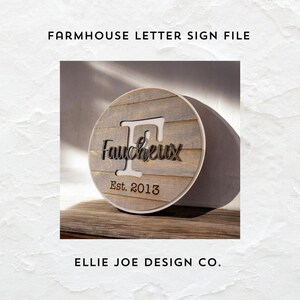 May include: A round wooden sign with a distressed wood finish. The sign features a large letter "F" with the name "Faucheux" written in a cursive font. The text "Est. 2013" is written below the name.