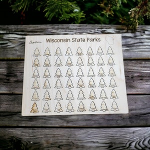 Peut inclure: Plaque en bois avec les mots "Wisconsin State Parks" et un contour de carte. La plaque présente une grille d'icônes d'arbres, chacune étiquetée avec un nom de parc. Le mot "Explore" est gravé dans le coin supérieur gauche.