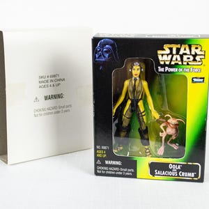 May include: A Star Wars action figure set featuring Oola and Salacious Crumb, packaged in a box with the text "The Power of the Force." The box has a black and green design with a Darth Vader image.