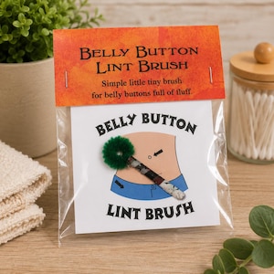 May include: A small belly button lint brush packaged in a clear plastic bag with an orange header card. The card features the text Belly Button Lint Brush and Simple little tiny brush for belly buttons full of fluff. The brush has a green fuzzy tip.
