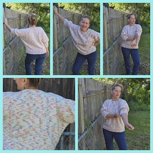 May include: A woman is wearing a white sweater with a multi-colored confetti pattern. The sweater has a relaxed fit and long sleeves. She is wearing blue jeans and is standing in front of a wooden fence.