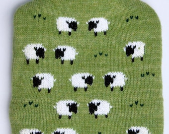 Knitted hot water bottle cover with grazing sheep design
