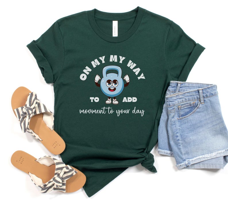 Puede incluir: Camiseta verde oscuro con el texto "ON MY WAY TO ADD movement to your day" y un personaje de pesa rusa de dibujos animados. La camiseta se combina con pantalones cortos vaqueros y sandalias con un estampado de rayas blancas y negras.