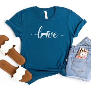 May include: Teal blue t-shirt with a white silhouette of a dog and the word "love" written in a cursive font.