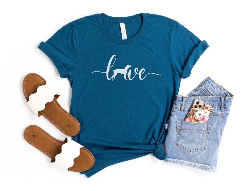 May include: Teal blue t-shirt with a white silhouette of a dog and the word "love" written in a cursive font.